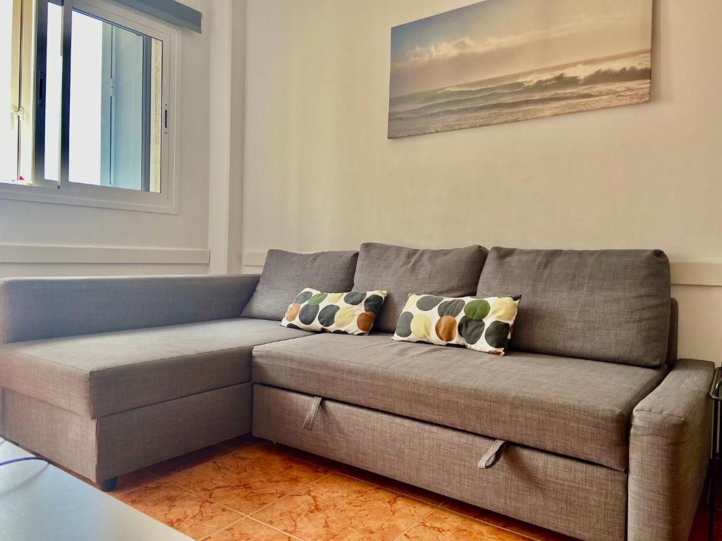 een grijze bank in een woonkamer met een raam bij Apartamento Allegra in Arinaga