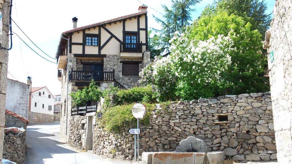 an old house with a stone wall and a street at Artesano I y III in Navarredonda de Gredos