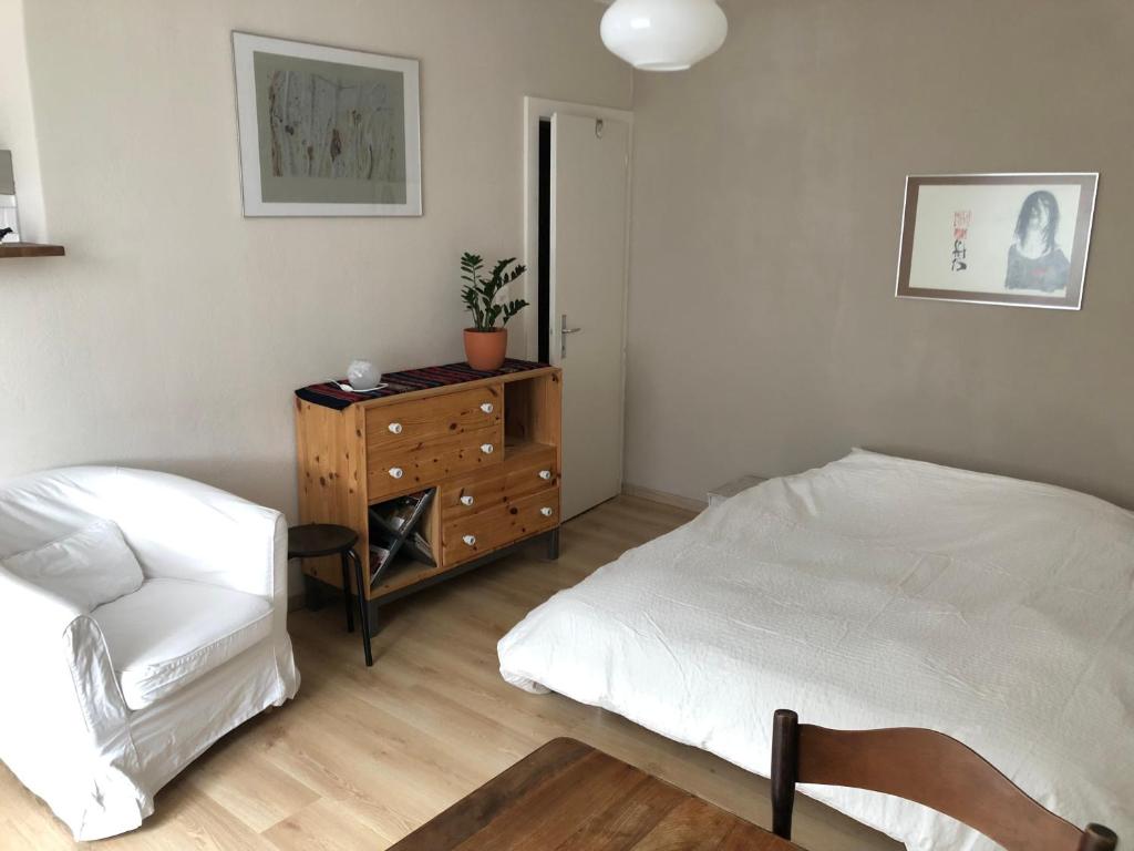 1 dormitorio con 1 cama, vestidor y silla en Joli studio renové avec goût proche de la gare en Le Locle