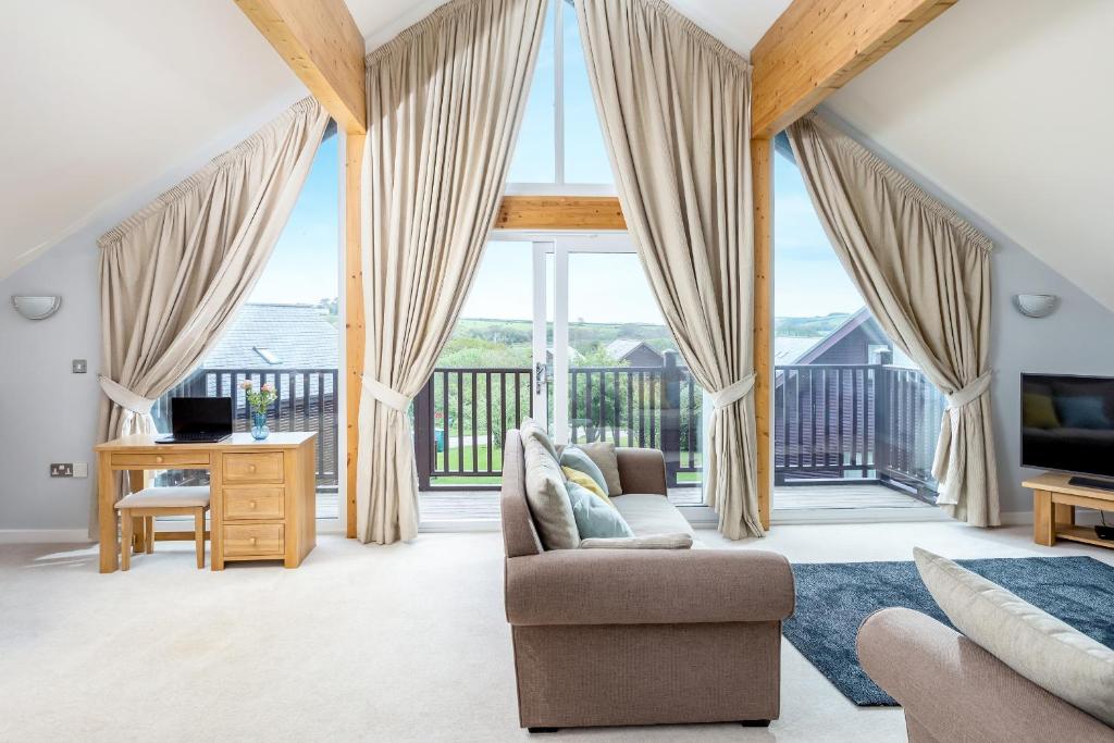 a living room with large windows and a couch at Sunbow at Retallack Resort in Saint Columb Major