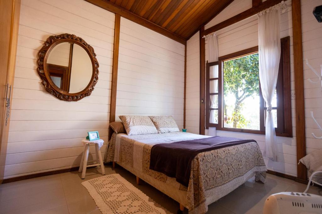 a bedroom with a bed and a mirror and a window at Cantareira - Deck House in Mairiporã