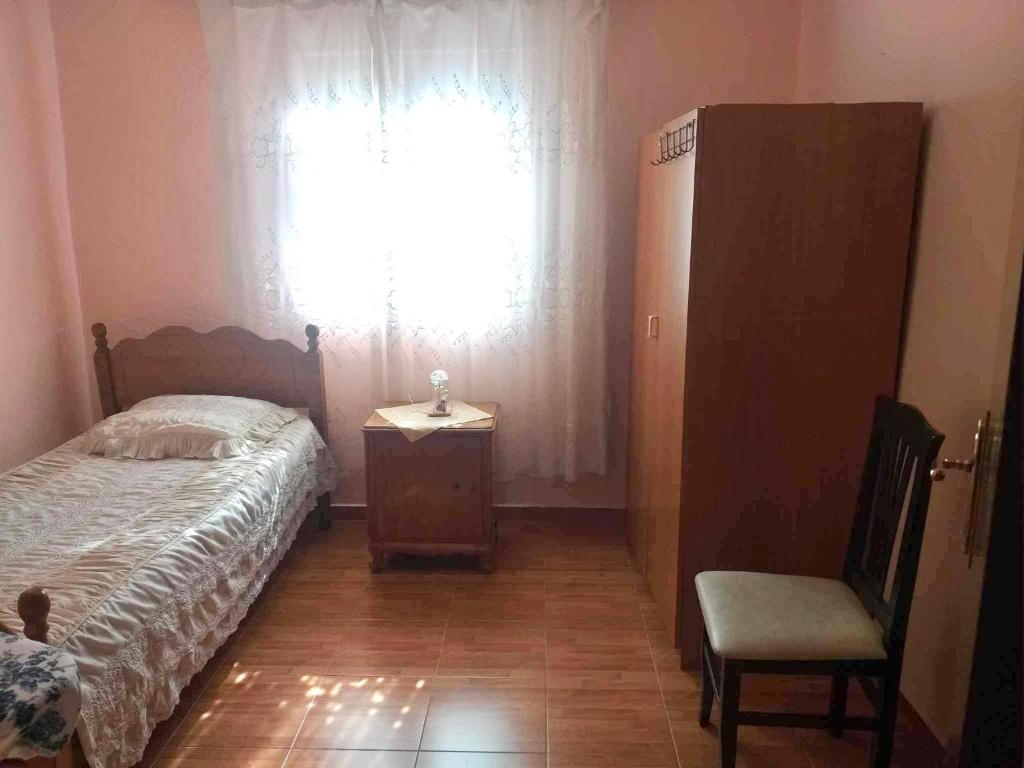 a bedroom with a bed and a chair and a window at Private village home in Përmet