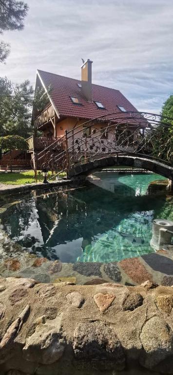 a house with a bridge over a swimming pool at Zielkowa Ostoja in Niesiołowice