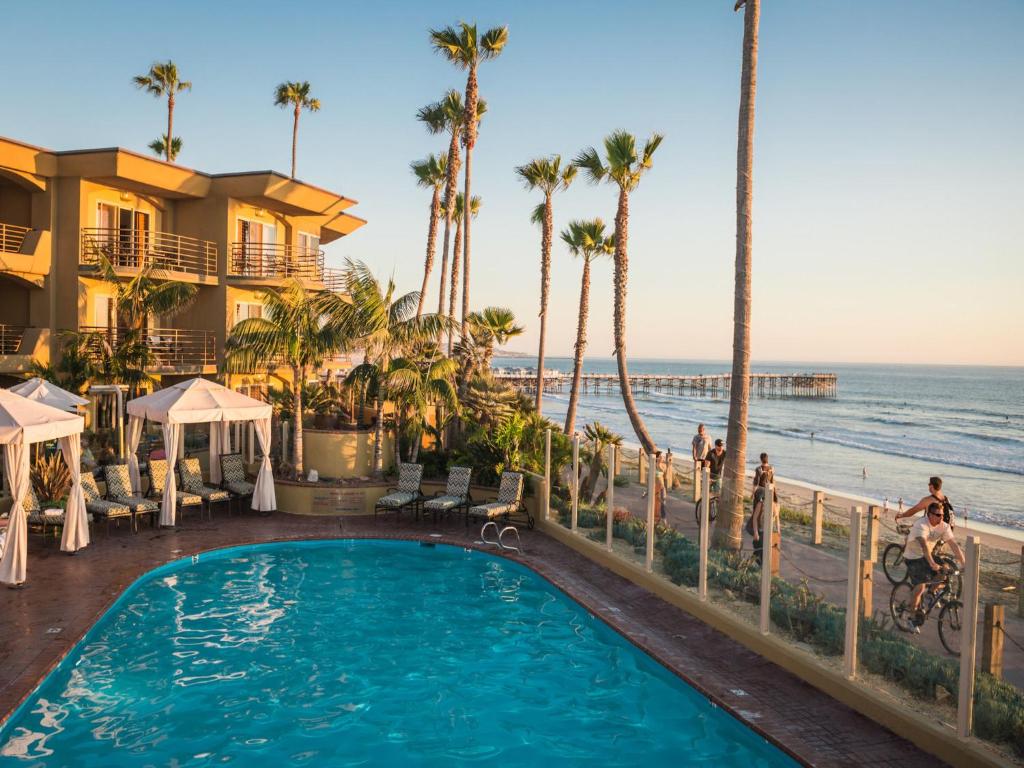 a swimming pool at a resort with the ocean in the background at Pacific Terrace Hotel in San Diego