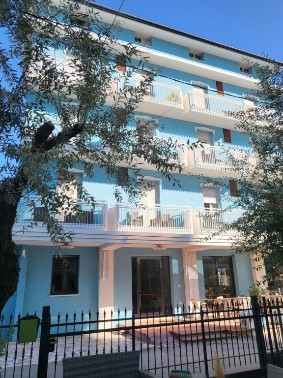 a white building with balconies and a fence at Hotel Lauretta in Bellaria-Igea Marina