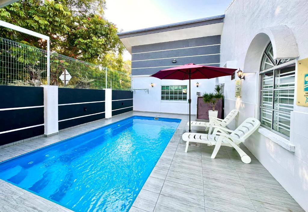 a swimming pool with two chairs and an umbrella at H&H 1 Guest House in Malacca