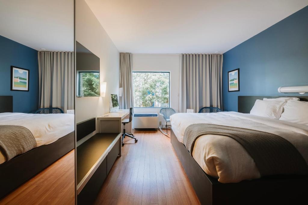 2 camas en una habitación de hotel con paredes azules en Le Dauphin St-Hyacinthe en Saint-Hyacinthe