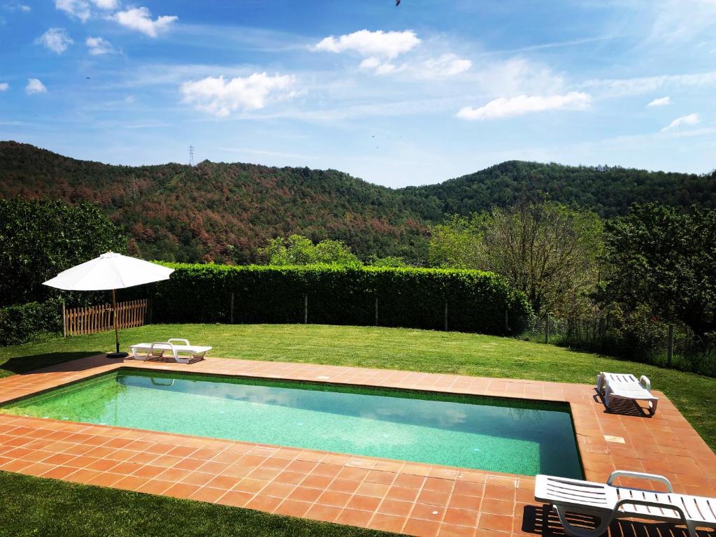 einen Pool in einem Garten mit Stühlen und einem Sonnenschirm in der Unterkunft Mas El Soler de Terrades - Turisme Rural in Moià