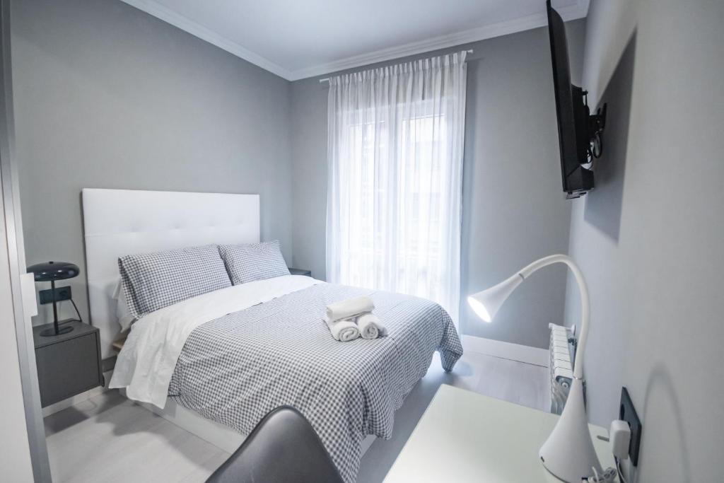 biała sypialnia z łóżkiem i lampką w obiekcie Gran Apartamento 6 SUITES Bilbao Center w mieście Bilbao
