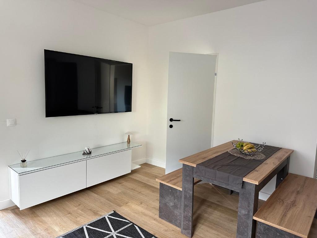 a living room with a table and a tv on the wall at Apartment Deluxe Rosenheim Top 1 