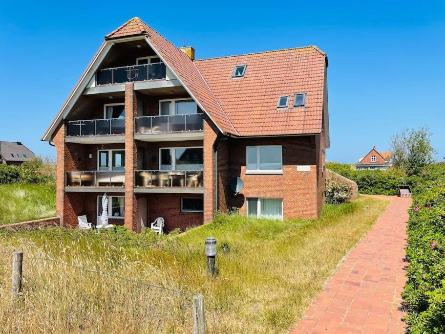 a brick house on top of a grassy hill at Düne 77 Moderne Ferienwohnung in Baltrum