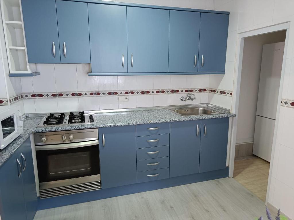 a kitchen with blue cabinets and a sink at Holiday apartment in Puerto de Sagunto