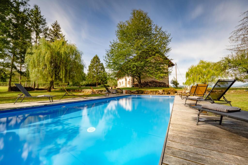 a swimming pool with chaise lounges and chairs in a yard at Domaine du Chypre in Cercier