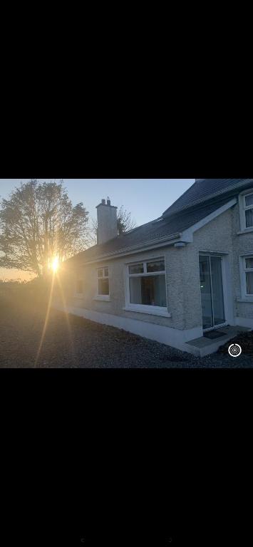 uma casa com o sol brilhando ao lado dela em Clonmines lodge em Wexford