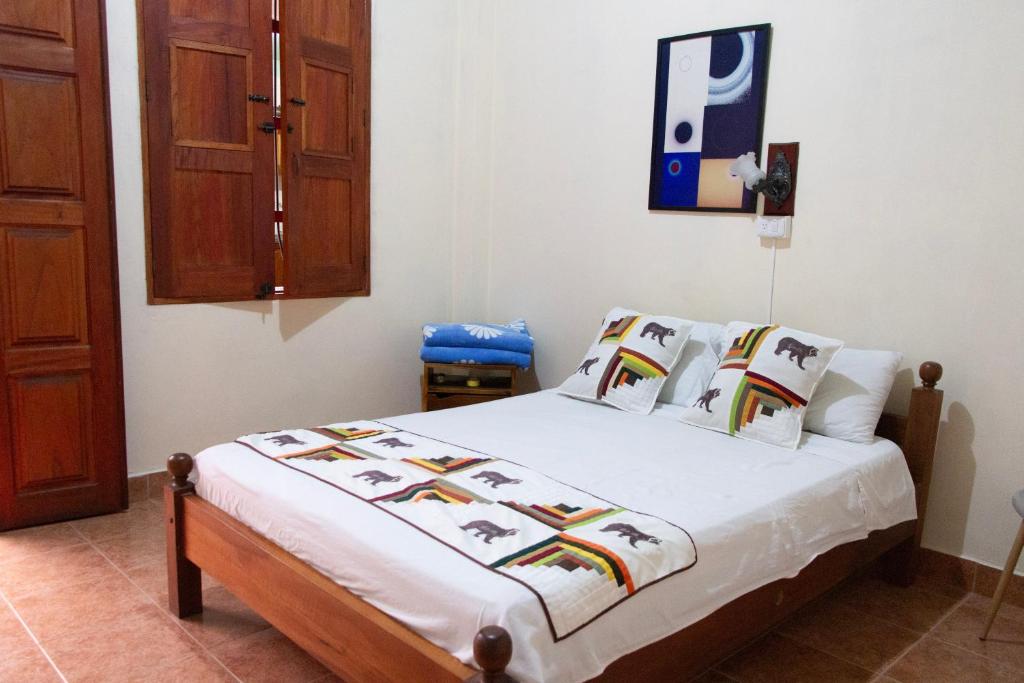 een slaapkamer met een bed met witte lakens en kussens bij Candileja hostel in Jardin