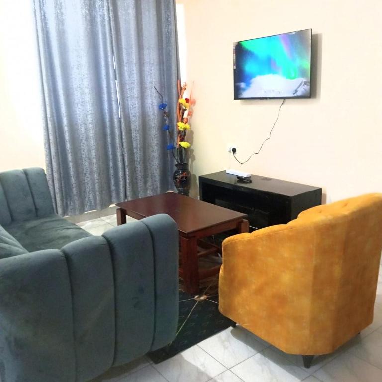 uma sala de estar com um sofá, uma mesa e uma televisão em Milly's homes em Kakamega