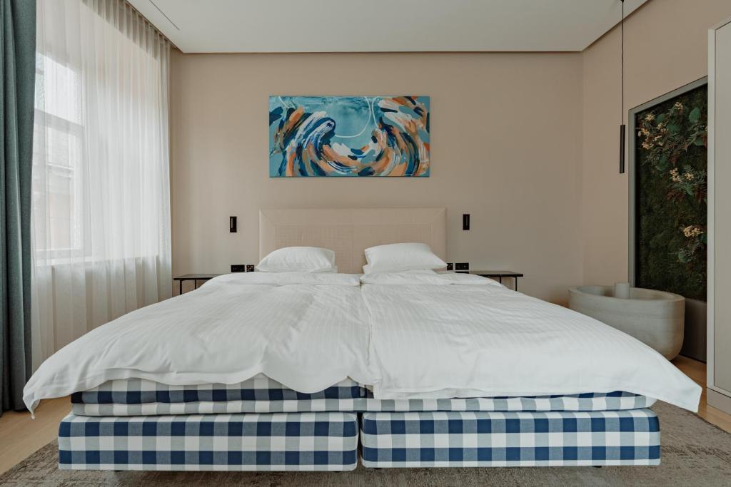 um quarto com uma cama com lençóis brancos e um quadro em Royal Marbles em Vilnius