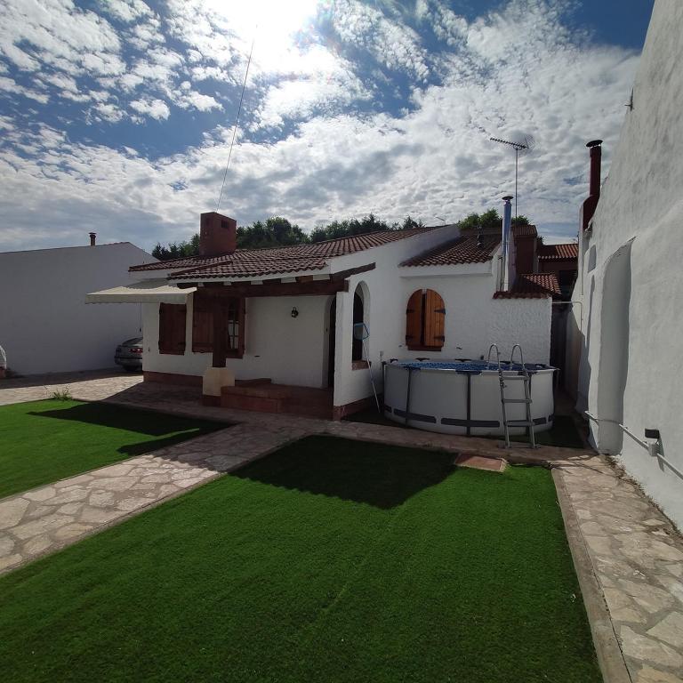 een wit huis met een tuin van groen gras bij EL COBIJO in Mojados