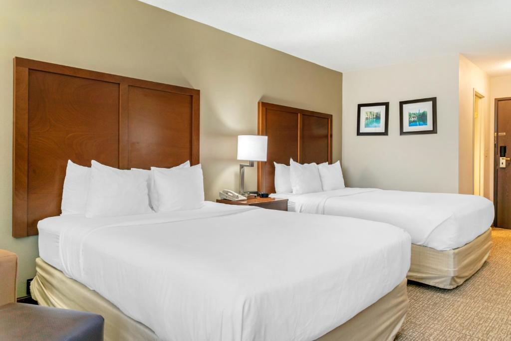 two beds in a hotel room with white sheets at Comfort Inn in Manistique