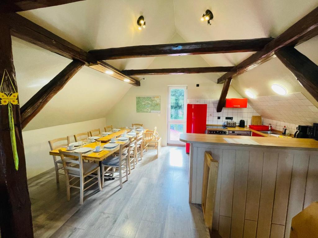a dining room with a long table and a kitchen at Haus am Bach in Neuwerk