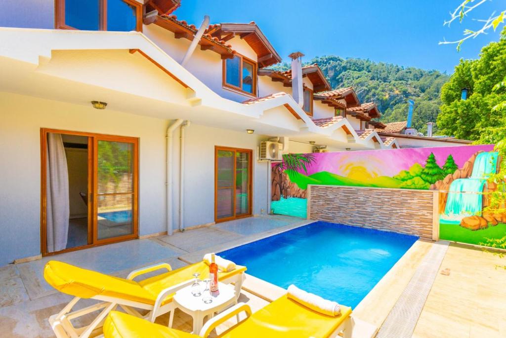 a villa with a swimming pool and yellow chairs at Villa Melek Paradise in Dalyan
