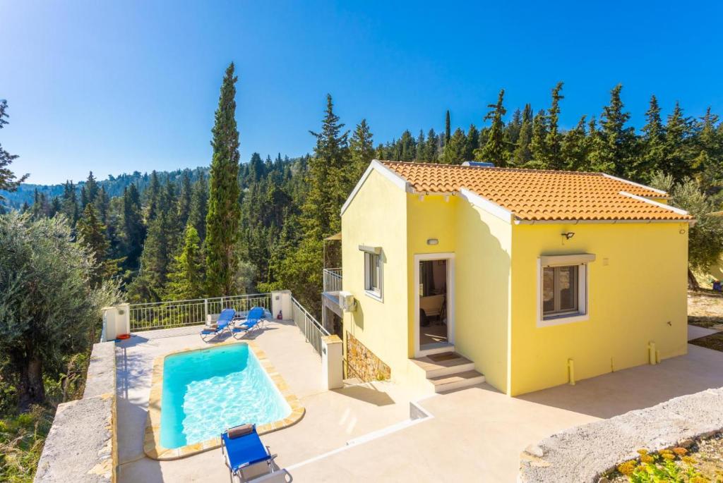 a small yellow house with a swimming pool on a patio at Villa Ifigeneia in Gaios