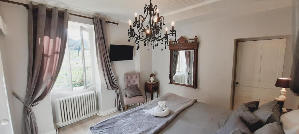 a bedroom with a chandelier with a swan sitting on a bed at LES TROIS L in Gindou