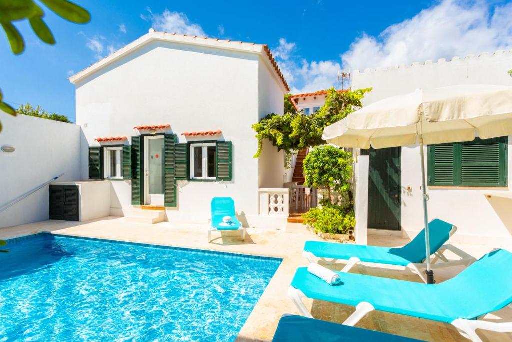 a villa with a swimming pool and blue chairs at Villa Torreta in Punta Prima