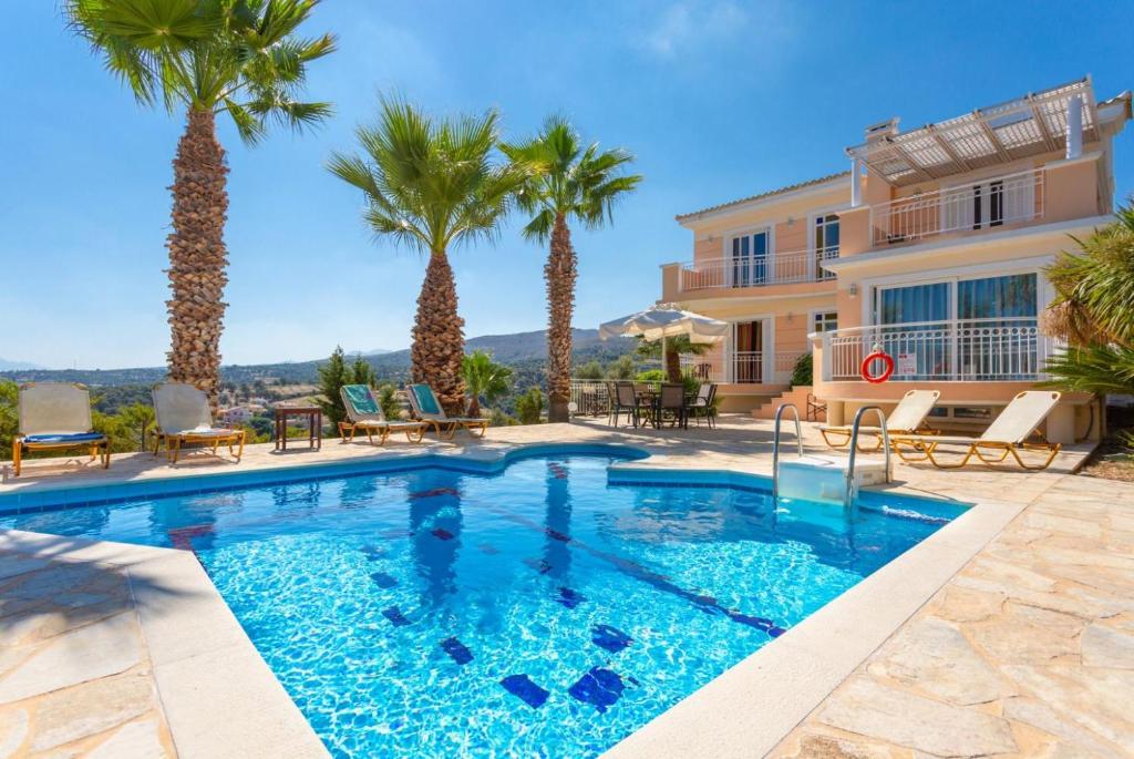 una piscina con palmeras frente a una casa en Villa Astro, en Agia Triada