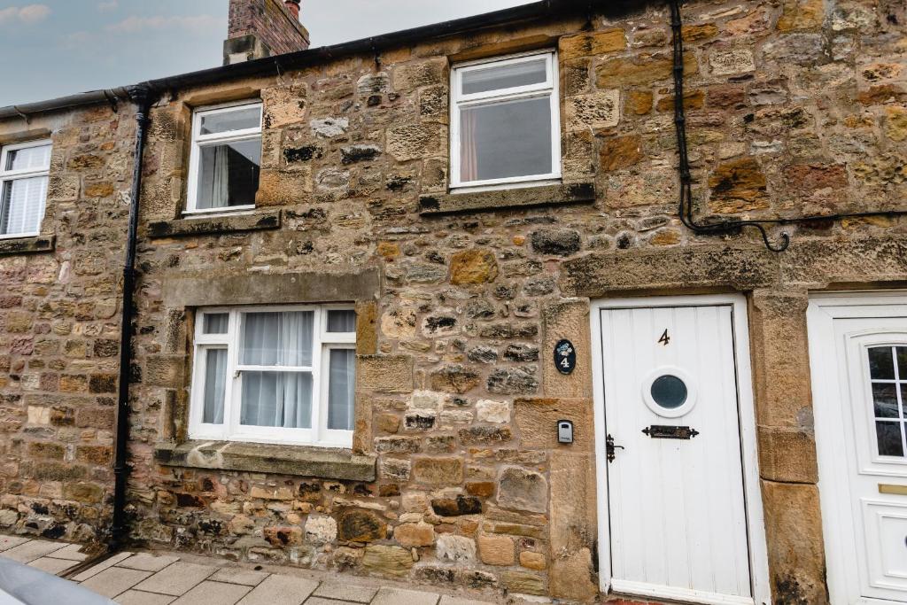 un edificio de ladrillo con una puerta y ventanas blancas en Percy Cottages No4, en Alnmouth