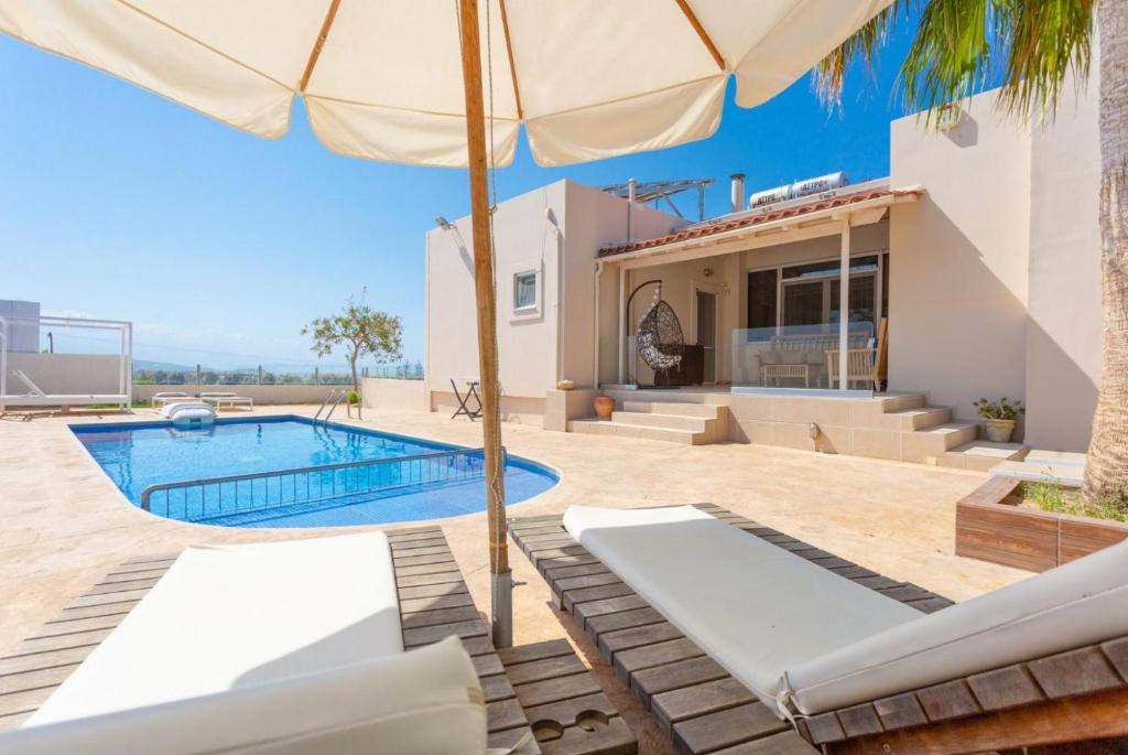 a villa with a swimming pool and an umbrella at Villa Thetis in Adelianos Kampos