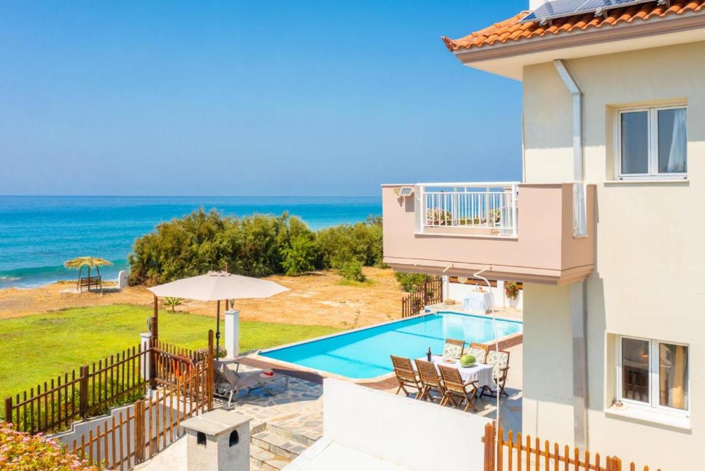 a villa with a swimming pool and the ocean at Kalisto Beach Villa in Kato Yialia