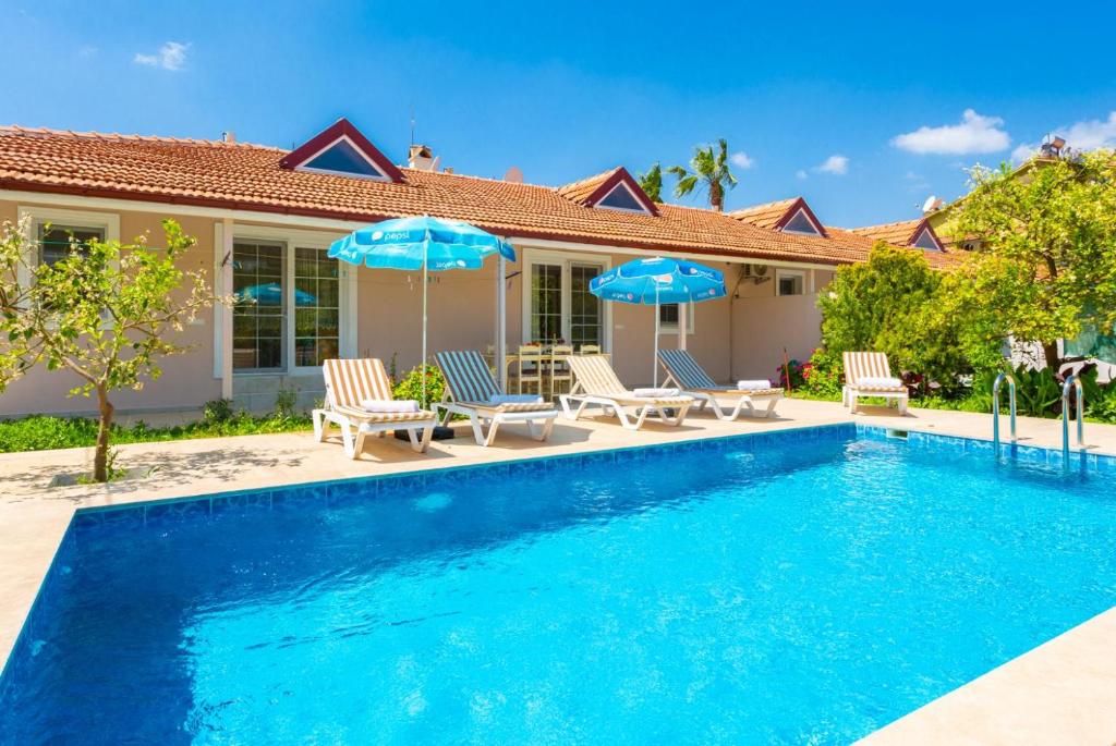 a swimming pool with chairs and umbrellas next to a house at Villa Duman 3 in Dalyan