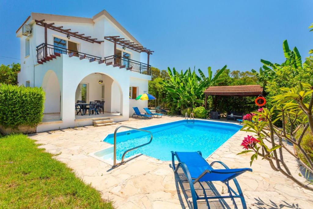 a villa with a swimming pool in front of a house at Sun Beach Villa Thio in Polis Chrysochous