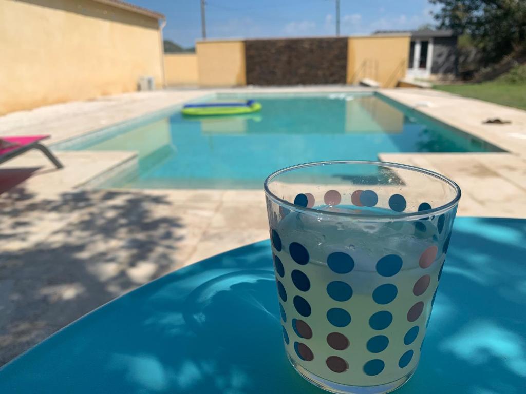 a glass of water sitting on a table next to a swimming pool at Villa et chalet avec piscine proche Aix & Luberon in Peyrolles-en-Provence