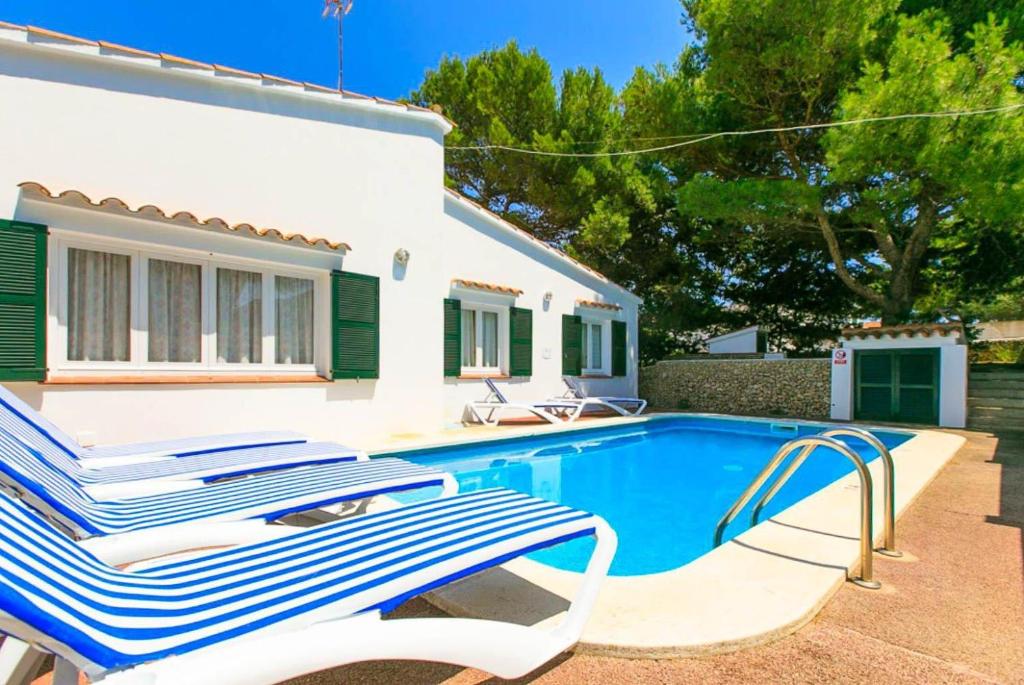 a swimming pool with two lounge chairs next to a house at Villa Trepuco Uno in Punta Prima