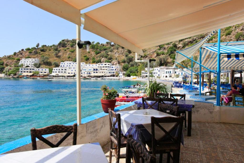 restauracja ze stołami i krzesłami nad wodą w obiekcie Spiros Beach Villa w mieście Frangokastello