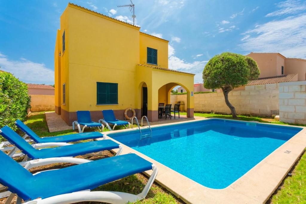 uma piscina em frente a uma casa com espreguiçadeiras azuis em Villa La Luna em Cala en Blanes