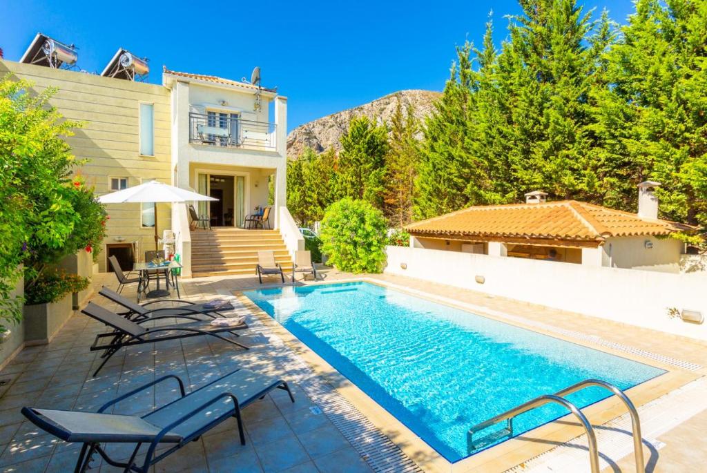 een zwembad met stoelen en een huis bij Villa Ismini in Kateliós