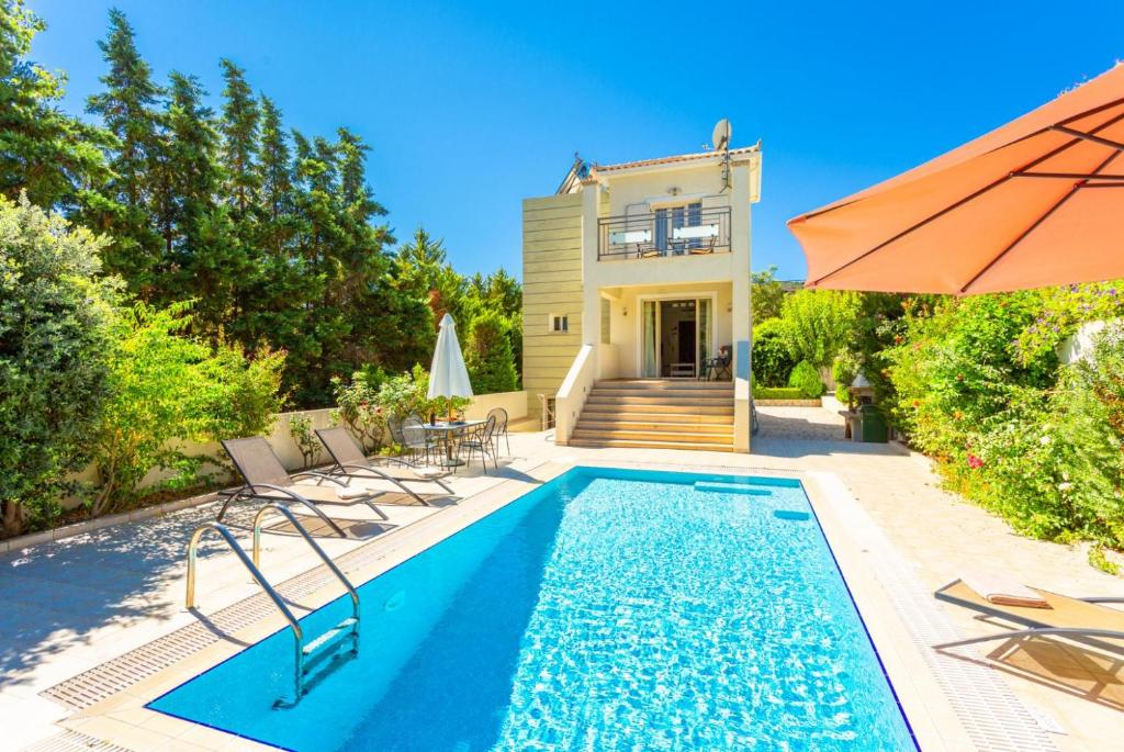 een zwembad voor een huis met een parasol bij Villa Semeli in Kateliós