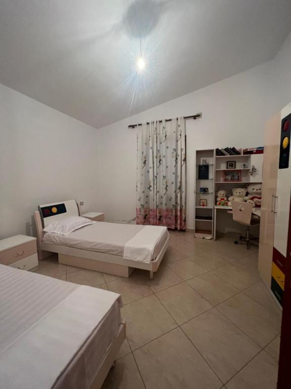 - une chambre avec 2 lits et un bureau dans l'établissement Cela House, à Divjakë