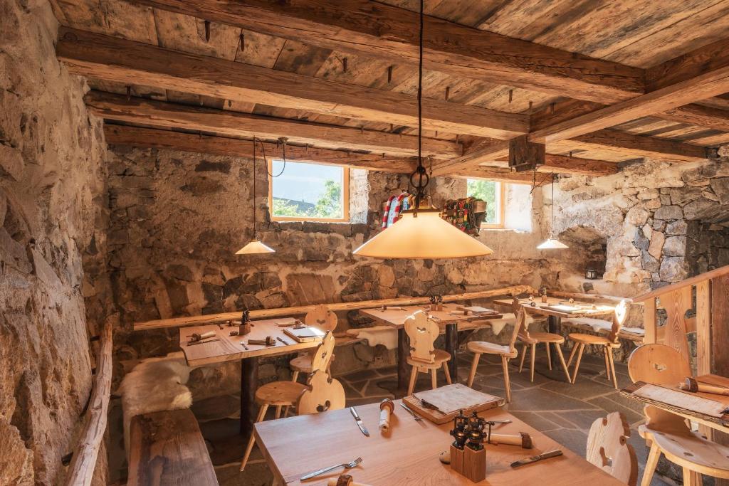 restauracja z drewnianymi stołami i krzesłami w pokoju w obiekcie Huberhof w mieście Fiè