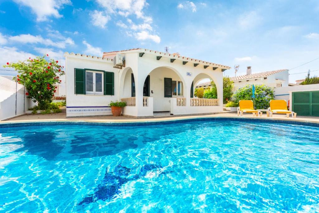 a villa with a swimming pool in front of a house at Villa Emilio in Cala'n Porter