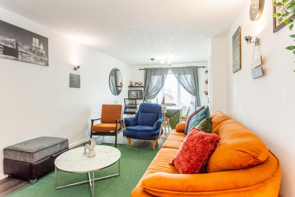 ein Wohnzimmer mit einem orangenen Sofa und Stühlen in der Unterkunft Unique Vintage Apartments in Goodmayes