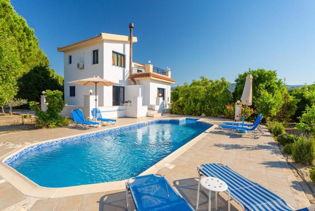 a villa with a swimming pool in front of a house at Villa Charoula Tessera in Polis Chrysochous