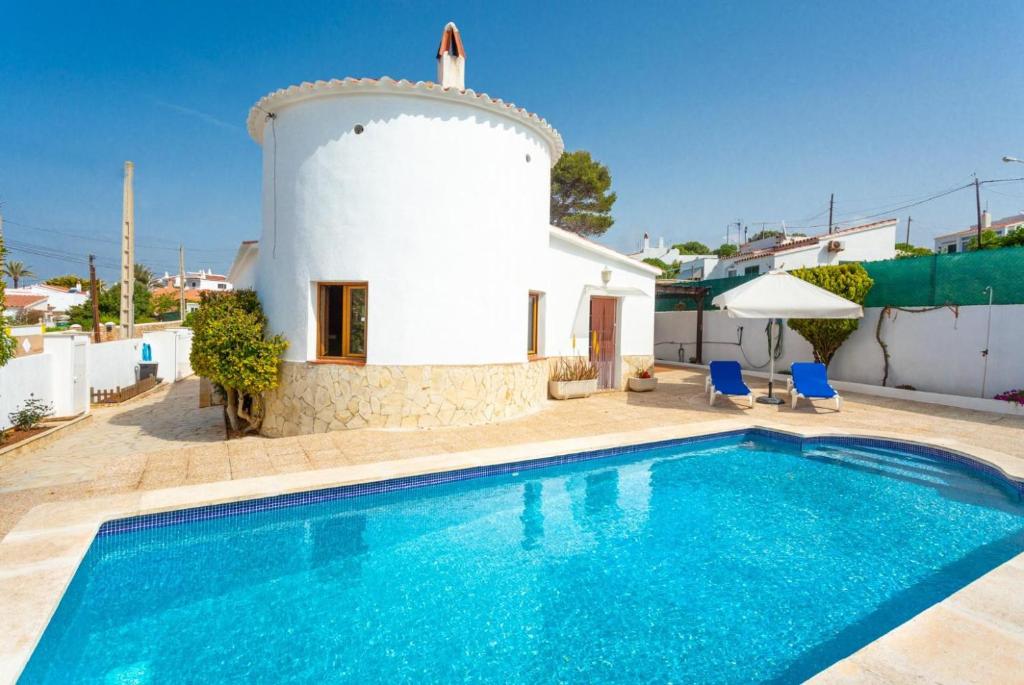 a villa with a swimming pool in front of a house at Villa Maria in Cala en Porter