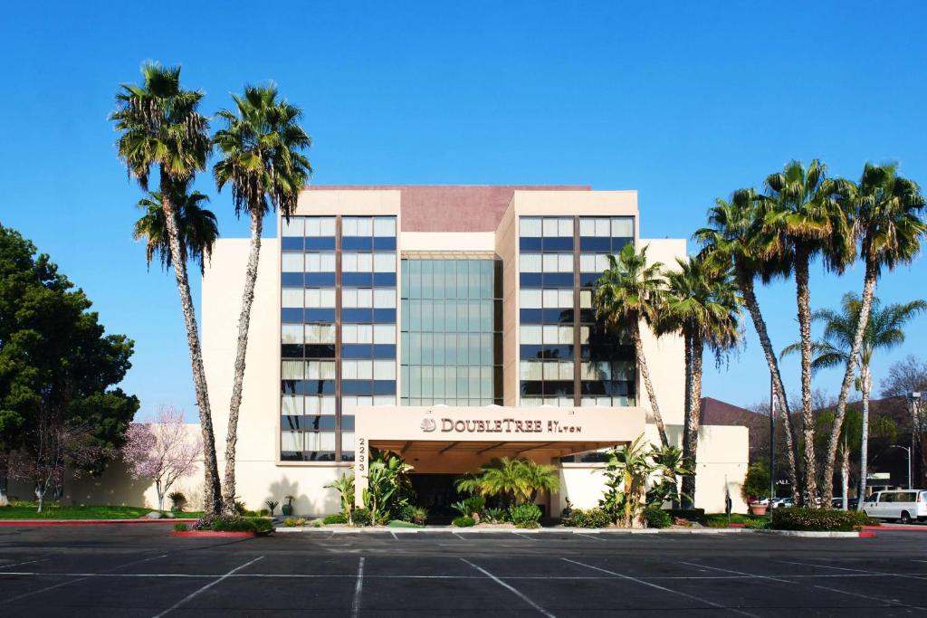 a hotel with palm trees in front of a parking lot at DoubleTree by Hilton Fresno Convention Center in Fresno