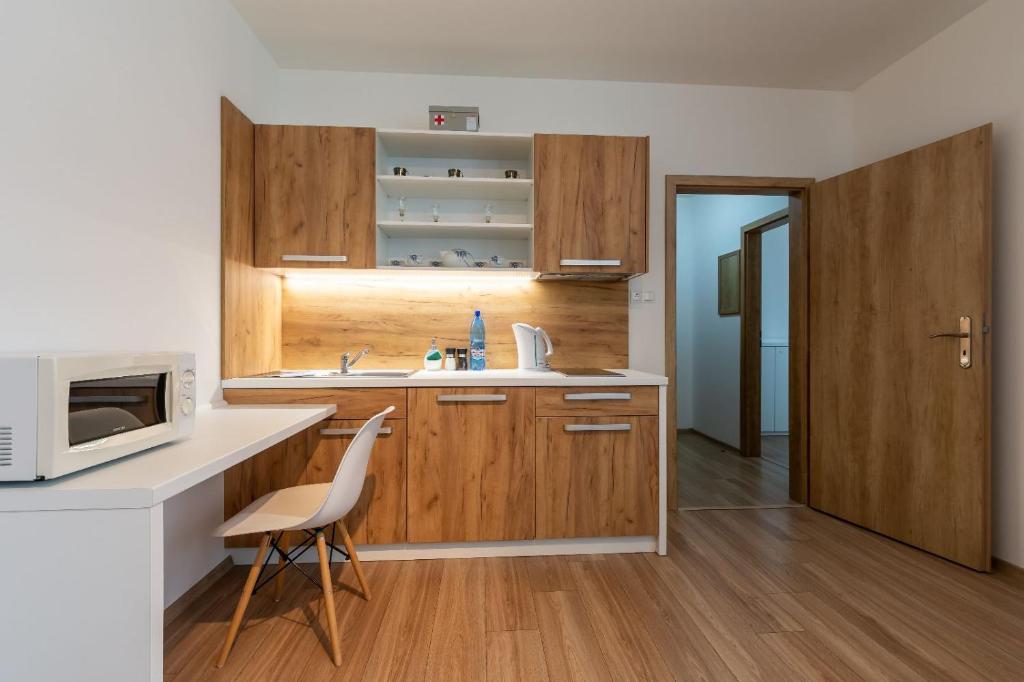 a kitchen with wooden cabinets and a sink and a microwave at Apartmán Janka in Liptovský Ján