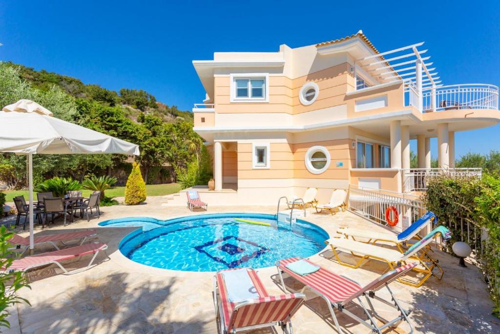a villa with a swimming pool in front of a house at Villa Asimenia in Agia Triada