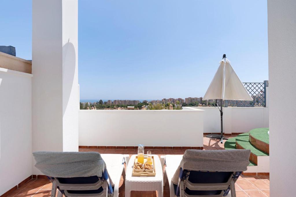 uma varanda com uma mesa e 2 cadeiras e uma vista em Townhouse with 3 bedrooms and sea views from the roof terrace em Torremolinos